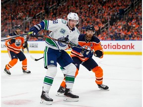 Adam Larsson, right, of the Edmonton Oilers battles against Tim Schaller of the Vancouver Canucks at Rogers Place on October 2, 2019, in Edmonton, Canada.