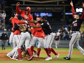 Patrick Corbin #46 (R) and Howie Kendrick #47 of the Washington Nationals celebrate with teammates after the final out of the tenth inning as the Nationals defeated the Los Angeles Dodgers 7-3 in game five to win the National League Division Series at Dodger Stadium on October 09, 2019 in Los Angeles, California. (Photo by Harry How/Getty Images)