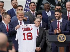 U.S. President Donald Trump holds a Boston Red Sox team jersey presented by outfielder and designated hitter J.D. Martinez as the president stands next to team owner John Henry (centre) as the president welcomes the 2018 World Series Champion Red Sox on the South Lawn at the White House in Washington, U.S. May 9, 2019.  REUTERS/Kevin Lamarque/File Photo