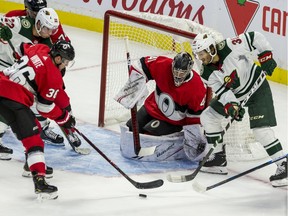 Ottawa Senators goaltender Craig Anderson holds his net against Minnesota Wild Ryan Hartman as Sens Colin White clears the puck during NHL action at thew Canadian Tire Centre on Monday.