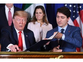 US President Donald Trump (L) and Canadian Prime Minister Justin Trudeau (R) along with Mexico's President Enrique Pena Nieto (out of frame) changes documents after signing a new free trade agreement in Buenos Aires, on November 30, 2018, on the sidelines of the G20 Leaders' Summit.