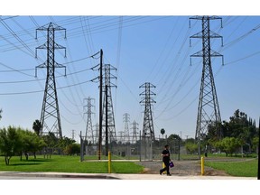 A pedestrian walks past a row of power lines in Rosemead, California on October 9, 2019, as southern California braces for the possibility of widespread power outages.