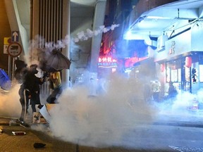 A protester throws back a tear gas canister fired by police in Sham Shui Po as a pro-democracy march was held in the Kowloon district in Hong Kong on October 20, 2019.