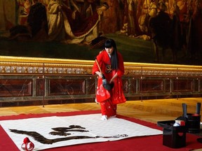 Japanese artist Yukako Matsui uses a traditional calligraphy brush and ink to write the name of Japan's new era of "Reiwa" ("beautiful harmony" in English) on paper in the hall of coronation of The Chateau de Versailles in Versailles, near Paris on October 21, 2019, in honour of the forthcoming coronation of Japan's new Emperor.
