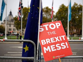 A placard belonging to an anti-Brexit activist leans against a European Union flag outside the Houses of Parliament in London on October 23, 2019.