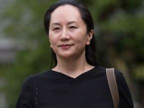 Huawei chief financial officer Meng Wanzhou, who is out on bail and remains under partial house arrest after she was detained last year at the behest of American authorities, carries one of her company's phones as she leaves her home to attend a court hearing in Vancouver, on Wednesday, Oct. 2, 2019.