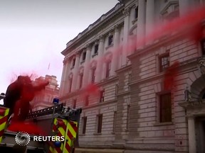 A climate protester loses control of a hose shooting a spray of fake blood at the U.K. Treasury building on Oct. 3, 2019.