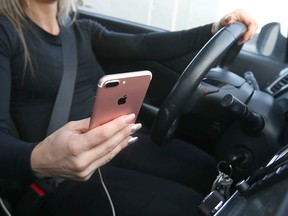 A driver checks her phone while behind the wheel in Calgary Saturday, January 12, 2019. Policesay theyve handed out fewer distracted driving tickets since penalties for the offence in Alberta were toughened a couple years ago. Jim Wells/Postmedia