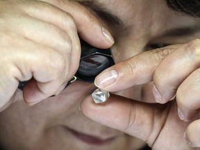 An employee inspects rough diamonds in Alrosa Diamond Sorting Centre in the town of Mirny on July 1, 2019. (ALEXANDER NEMENOV/AFP/Getty Images)