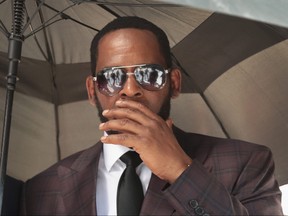 R&B singer R. Kelly covers his mouth as he speaks to members of his entourage as he leaves the Leighton Criminal Courts Building following a hearing on June 26, 2019 in Chicago, Illinois.