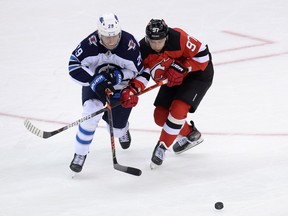 Winnipeg Jets right wing Patrik Laine and New Jersey Devils left wing Nikita Gusevbattle for the puck during the overtime period at Prudential Center in ; Newark, N.J., on Oct. 4, 2019.