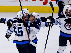 Jets’ Mark Scheifele (55) is swarmed by teammates, including Jack Roslovic, after scoring the winning goal in overtime against the Blackhawks in Chicago on Saturday night. Scheifele’s goal was his second of the season. (THE ASSOCIATED PRESS)