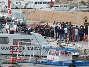 Rescue personnel carry a stretcher off a rescue vessel, after a ship carrying some 50 migrants began taking on water off the coast of Lampedusa, Italy Oct. 7, 2019.