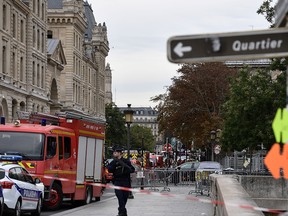 Police stand near a firefighter vehicle near Paris prefecture de police (police headquarters) on Oct. 3, 2019.