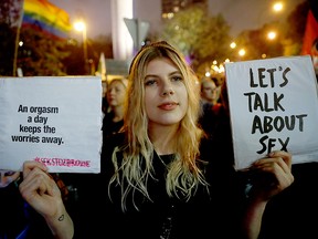 A demonstrator holds placards during a protest against a bill that would criminalise "the promotion of underage sex" in front of the Parliament in Warsaw, Poland, Oct. 16, 2019.