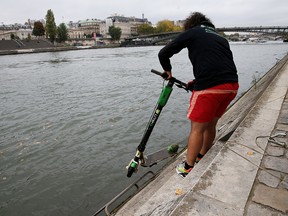 An employee of bicycle sharing service Lime fishes an abandoned electric scooter Lime-S out of the River Seine in Paris, October 25, 2019. (REUTERS/Pascal Rossignol)