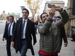 A bystander takes a selfie as Prime Minister Justin Trudeau walks to a news conference on October 23, 2019 in Ottawa. (DAVE CHAN/AFP via Getty Images)