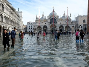 Tourists walk in St. Mark’s Square after days of severe flooding in Venice, Italy, Nov. 16, 2019. (REUTERS/Manuel Silvestri)