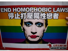 This file photo taken on February 7, 2014 shows an activist holding a placard with a slogan over the face of Russian President Vladimir Putin depicted with make-up during a demonstration against Russia's anti-gay legislation on the day of the opening ceremony the Sochi Winter Olympic Games in Hong Kong.