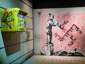 This picture taken on October 15, 2019 shows a replica of British street artist Banksy's artwork entitled "Little girl covering a Swastika" displayed as part of the exhibition "The world of Banksy, the immersive experience" at the Espace Lafayette-Drouot in Paris.