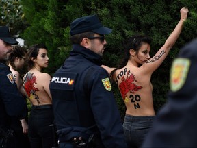 Spanish policemen surround members of the feminist movement Femen as they protest against a far right demonstration marking the anniversary of the death of Spanish late dictator Francisco Franco in Madrid on Nov. 24, 2019. (OSCAR DEL POZO/AFP via Getty Images)