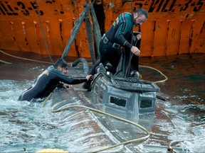 Spanish Civil Guard divers stand over the refloated prow of a submarine used to transport drugs illegally in Aldan, northwestern Spain, on Nov. 26, 2019. (LALO R. VILLAR/AFP via Getty Images)