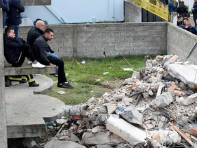 Onlookers watch as Italian rescuers search for bodies through the rubble of a collapsed building in Thumane, after an earthquake hit Albania, on Wednesday, Nov. 27, 2019.