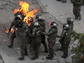Riot police officers who are on fire are assisted by fellow officers during a protest against Chile's government in Santiago, Chile, Nov. 4, 2019.