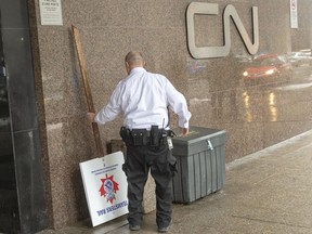A security guard removes a picket sign in front of the CN headquarters as Canadian National Railway workers begin a nationwide strike Tuesday, November 19, 2019 in Montreal.