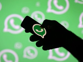 A man poses with a smartphone in front of displayed Whatsapp logo in this illustration picture September 14, 2017.