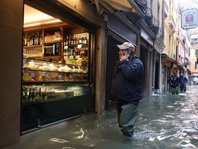 A man walks in a flooded street during a period of seasonal high water in Venice, Italy, November 17, 2019. (REUTERS/Manuel Silvestri)