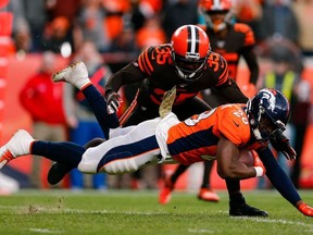 Denver Broncos running back Royce Freeman is tripped up running the ball as Cleveland Browns safety Jermaine Whitehead defends in the third quarter at Empower Field at Mile High.
