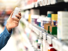 Customer in pharmacy holding medicine bottle. Woman reading the label text about medical information or side effects in drug store. Patient shopping pills for migraine or flu.