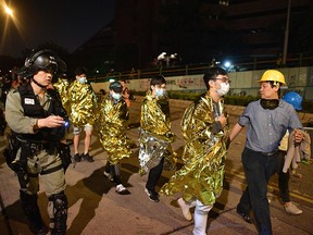 Unwell and injured protesters wrapped in emergency thermal blankets leave the campus of the Hong Kong Polytechnic University in Hong Kong on November 19, 2019. (NICOLAS ASFOURI/AFP via Getty Images)