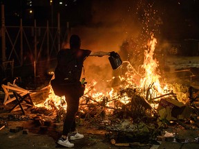 A protester pours petrol onto a burning barricade at the Chinese University of Hong Kong (CUHK), in Hong Kong early on November 13, 2019. - Hong Kong pro-democracy protesters fought intense battles with riot police on a university campus and paralysed the city's upmarket business district Tuesday, extending one of the most violent stretches of unrest seen in more than five months of political chaos.