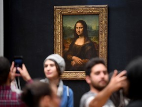 Visitors take pictures in front of Mona Lisa after it was returned at its place at the Louvre Museum in Paris on October 7, 2019. (ERIC FEFERBERG/AFP via Getty Images)