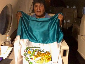 Former Bolivian president Evo Morales holds a Mexican flag onboard a Mexican government's aircraft in an unidentified location Nov. 11, 2019.