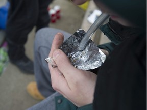A drug-user smoking fentanyl at Oppenheimer Park in Vancouver, BC Friday, May 3, 2019.