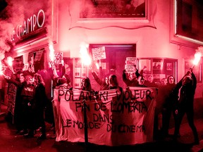 Demonstrators hold banners reading "Polanski rapist" as they hold flares during a protest against French-Polish film director Roman Polanski outside a cinema hall in Paris on Nov. 12, 2019.