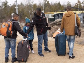 A family, claiming to be from Colombia, gets set to cross the border into Canada from the United States as asylum seekers on Wednesday, April 18, 2018 near Champlain, NY.