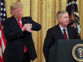 U.S. President Donald Trump checks his watch as Senator Lindsey Graham (R-SC) speaks during an event to celebrate federal judicial confirmations in the East Room of the White House in Washington, D.C., on Wednesday, Nov. 6, 2019.