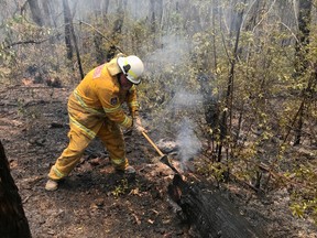 A volunteer from the New South Wales Rural Fire Service works to extinguish spot fires following back burning operations in Mount Hay, in Australia’s Blue Mountains, Dec. 28, 2019. (REUTERS/Jill Gralow)