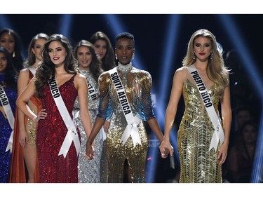 (L-R) Miss Mexico Sofia Aragon, Miss South Africa Zozibini Tunzi and Miss Puerto Rico Madison Anderson hold hands on stage during the 2019 Miss Universe pageant at the Tyler Perry Studiosin Atlanta, Ga., on Dec. 8, 2019.