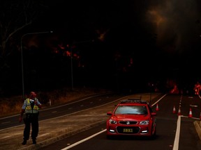 A New South Wales Police officer prepares to flee his roadblock on the Princes Highway near the town of Sussex Inlet on Tuesday, Dec. 31, 2019 in Sydney, Australia.