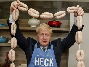 Boris Johnson, a leadership candidate for Britain's Conservative Party, holds up a string of sausages around his neck during a visit to Heck Foods Ltd. headquarters, as part of his Conservative Party leadership campaign tour near Bedale, Britain July 4, 2019.