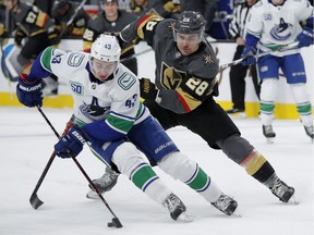 Vancouver Canucks' rookie defenceman Quinn Hughes skates around Vegas Golden Knights' left-winger William Carrier during Sunday's NHL action in Sin City. As Hughes points he will start earning bonuses, which could became a salary cap issue for the team down the road.