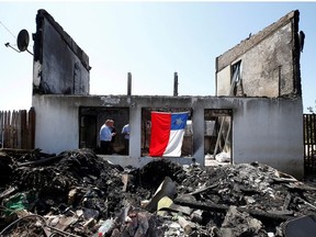 A Chilean flag hangs off the remains of a house, after it was destroyed by fire, following the spread of wildfires in Valparaiso, Chile  December 26, 2019.