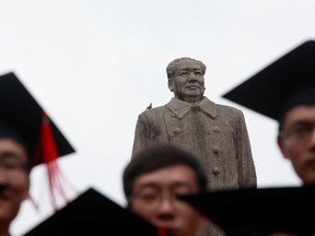 Graduates pose for a picture in front of the statue of late Chinese leader Mao Zedong after their graduation ceremony at Fudan University in Shanghai June 28, 2013.