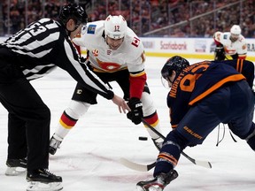 The Edmonton Oilers' Ryan Nugent-Hopkins takes a face-off against the Calgary Flames' Milan Lucic during first-period NHL action at Rogers Place, in Edmonton Friday.