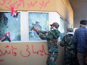 Members the Hashed al-Shaabi, a mostly Shiite network of local armed groups trained and armed by powerful neighbour Iran, smash the bullet-proof glass of the U.S. embassy's windows in Baghdad after breaching the outer wall of the diplomatic mission on December 31, 2019. (AHMAD AL-RUBAYE/AFP via Getty Images)